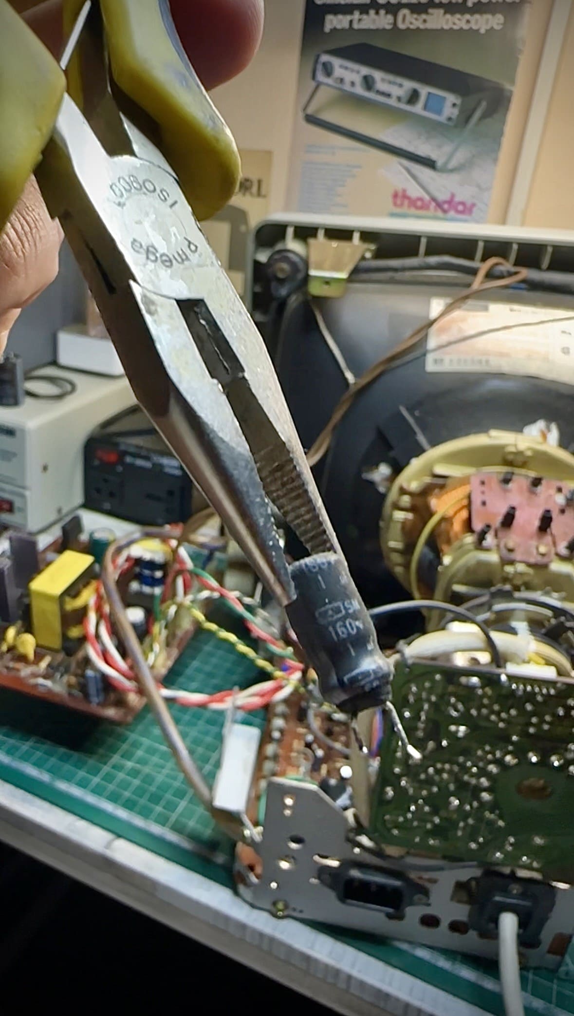 Rimozione di un condensatore danneggiato con pinza a punta durante la riparazione